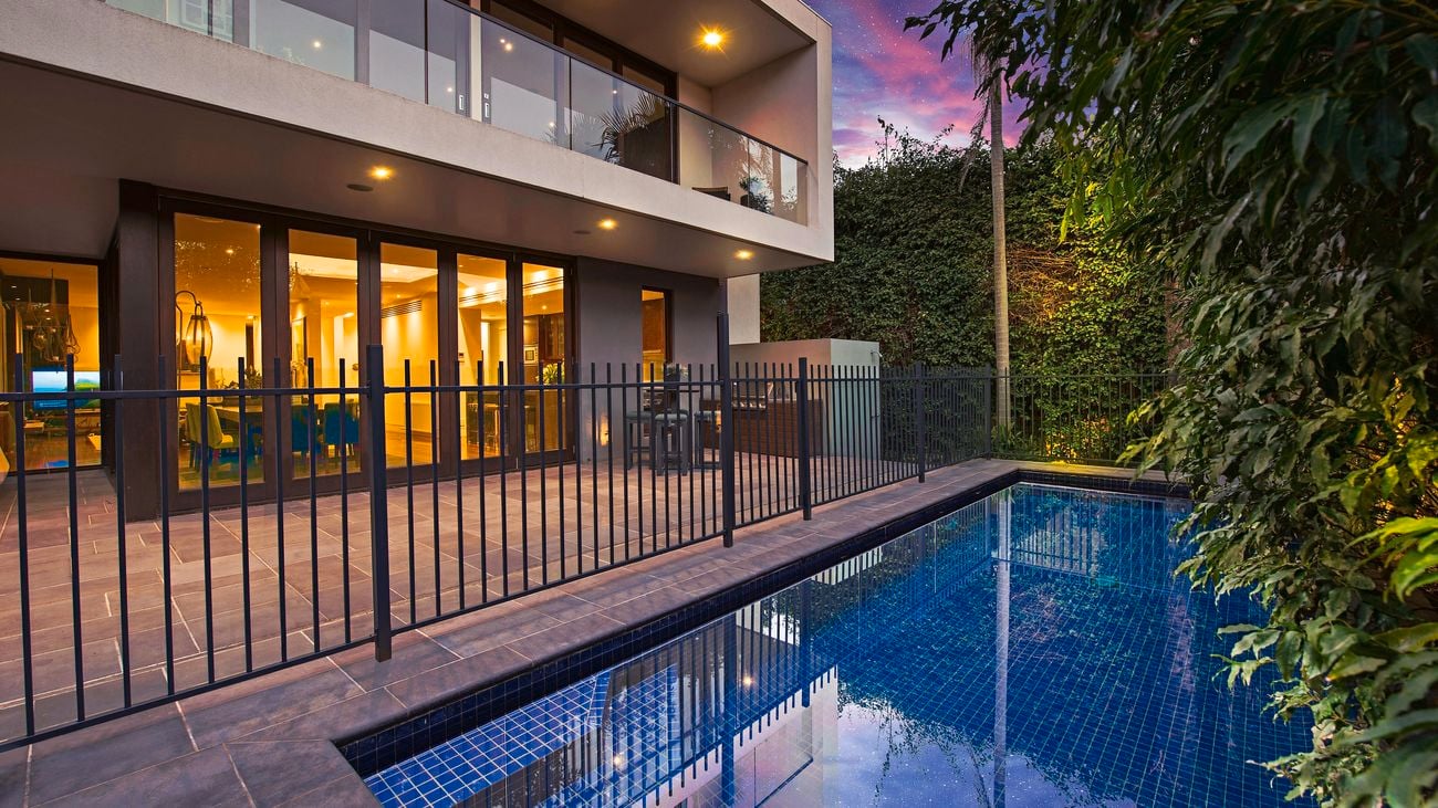 House with a swimming pool in a backyard, surrounded by a fence.