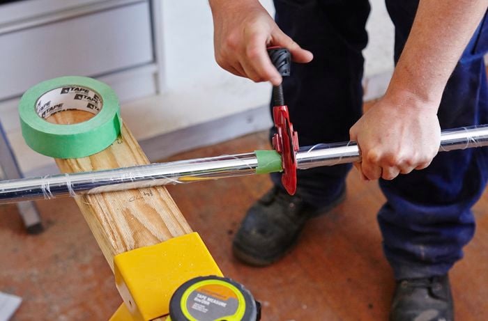 Person cutting metal rod that will be used as a wardrobe rod.