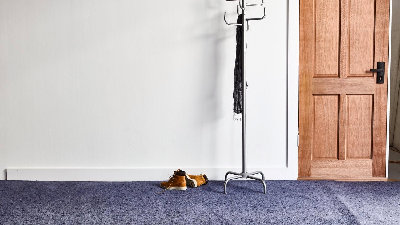 Room with carpet, coat rack and boots on the floor
