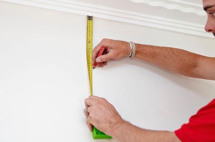 A tape measure and pencil being used to plot out the ideal place to install a wall plug