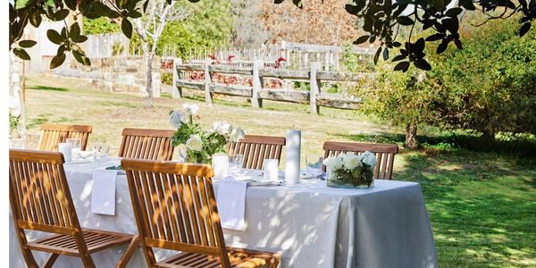 Backyard wedding table setting with natural hessian tablecloth, wooden seating and white flowers