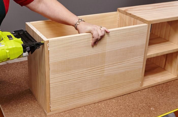 The storage space of a kids' bench being assembled with a power drill