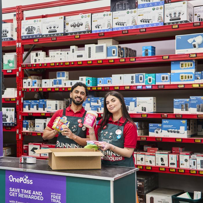 Two Bunnings TM's holding products at a desk in a Bunnings store.