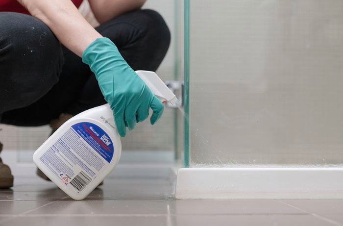 A person with green gloves is spraying Selleys mould killer onto the affected surface.