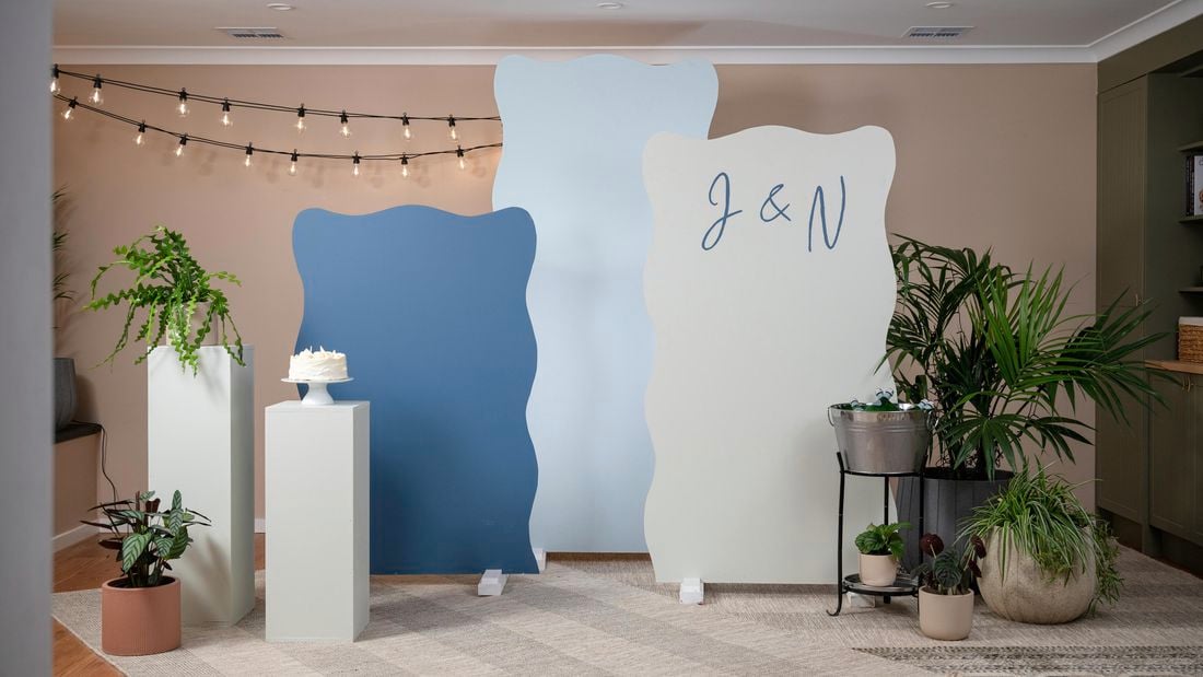 Blue and beige party backdrop trio surrounded by potted plants
