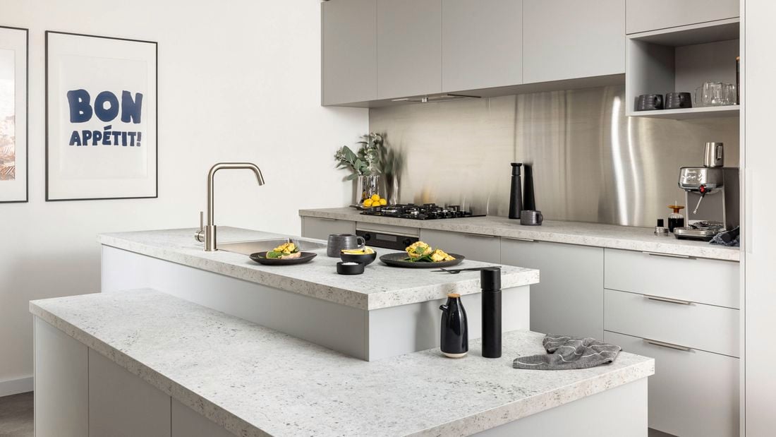 A mid shot of an urban edge style kitchen, with kitchen bench, cooktop, fridge and cupboards.