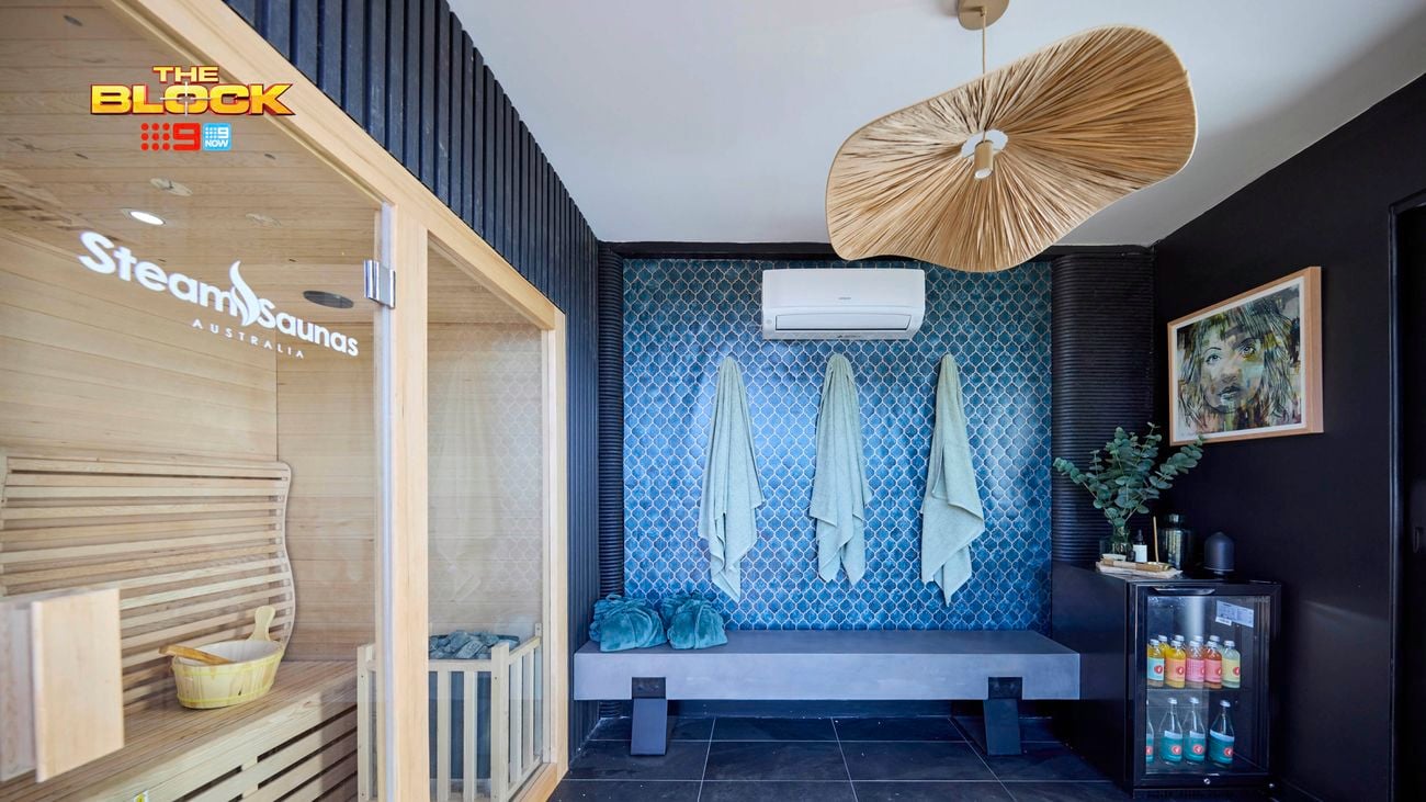 A room with towels hanging on hooks on a wall, tiled flooring, a split system attached to a wall and a print hanging on it also.
