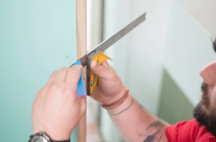 Marks a straight line on wood with a combination square and pencil. 