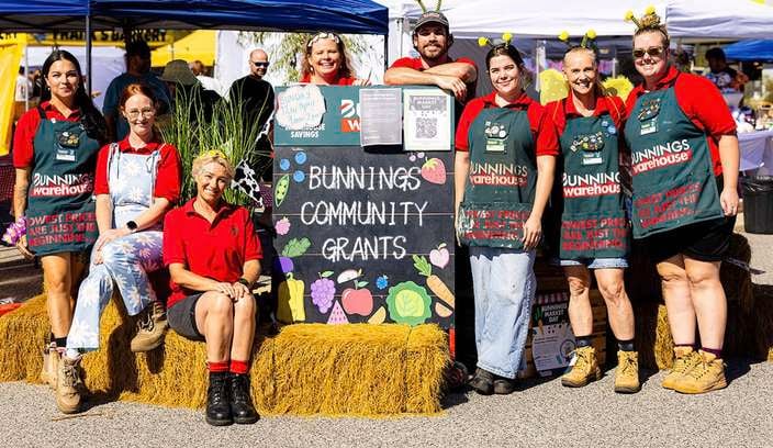 Bunnings Team Member's around bails of hay at a community event.