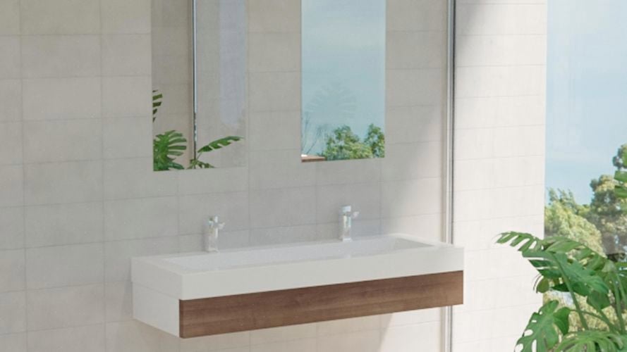 Bathroom with two mirrors along with large wash basin with two taps, plant and white wall tiles.