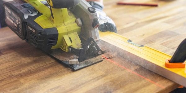 Close up of circular saw from a power tool kit cutting through timber with a laser line and spirit level.