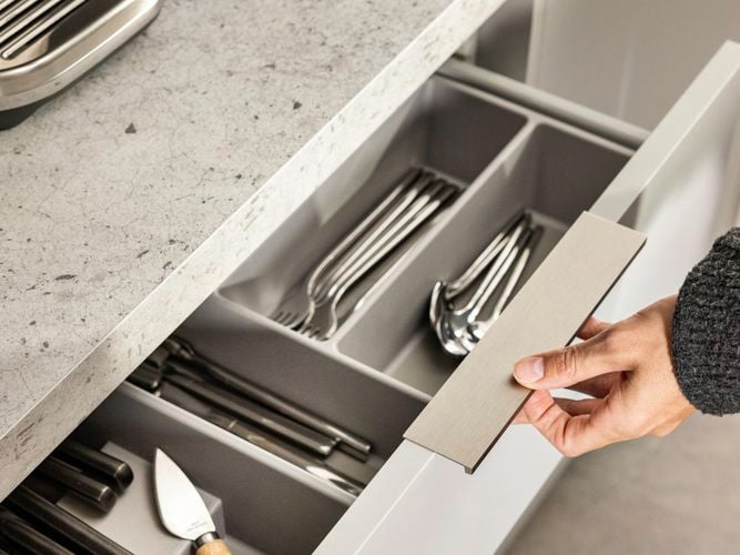 Kitchen with a marble benchtop and a drawer underneath it open with cutlery in it.