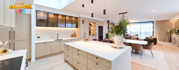 Modern open-plan kitchen and dining area featuring a large island bench, light timber cabinetry, pendant lighting and skylights.