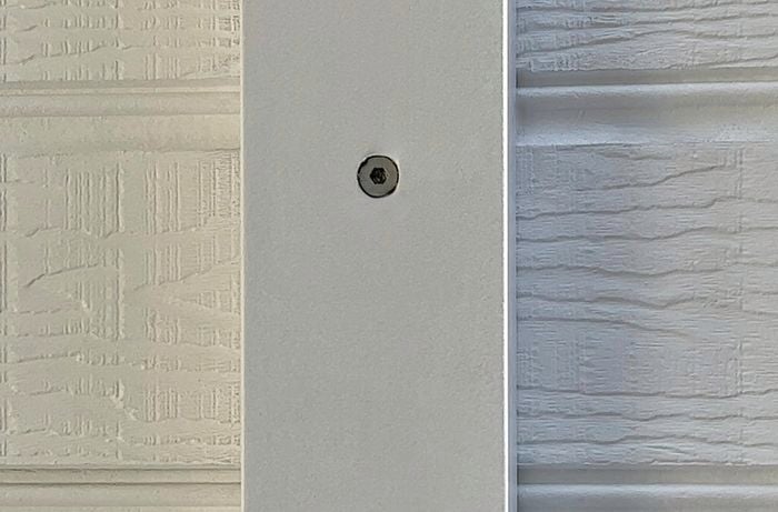 Close-up shot of a white wall with a screw in.