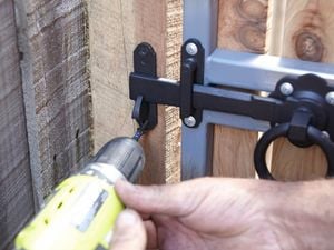 Person fixing a latch for a ring latch gate using a cordless driver