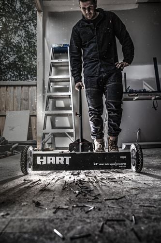 A tradesman using a magnetic sweeper to collect stray nails and bolts from a worksite