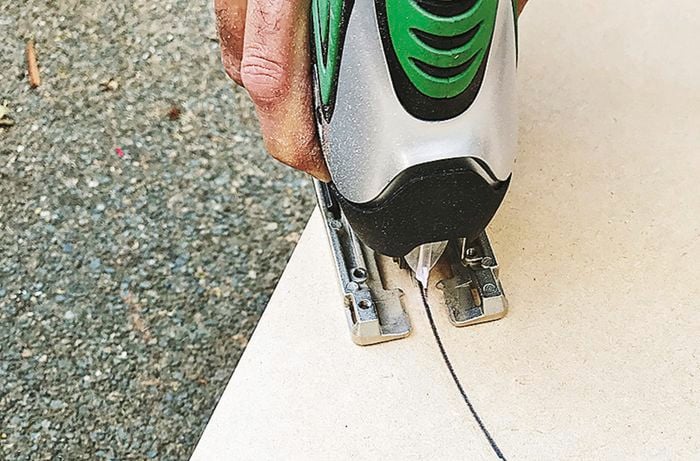 A person cutting the marked circle using a jigsaw.