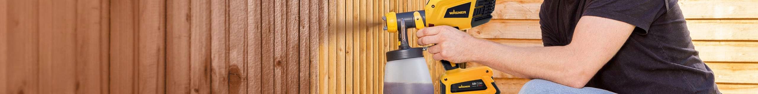 A person spray painting a fence.