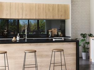 Kitchen with concrete floors, timber cabinets and black benchtop.