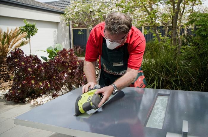 Person using an electric sander to remove paint from a door.