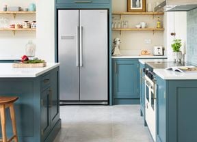 Teal kitchen with gold accents and large silver double door fridge.