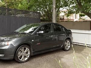 A steel grey Mazda SP23 is parked in the shade of a tree.