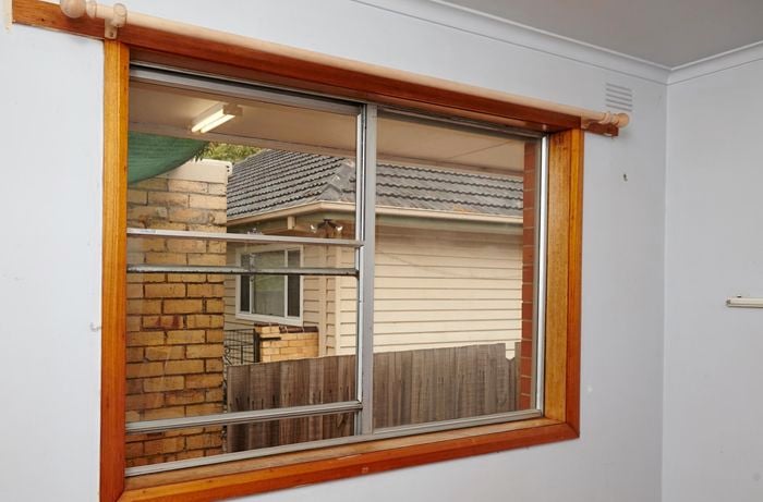 Window with brown timber frames, looking out to other houses next door.