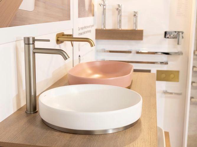Different coloured bathroom sinks and taps in a display area.