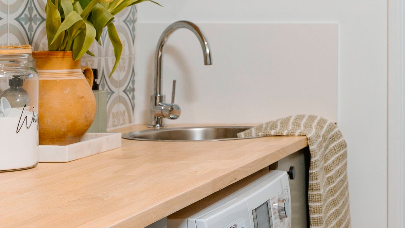 Timber bench tops in a laundry with chrome taps and sinks with brwon hand towel.