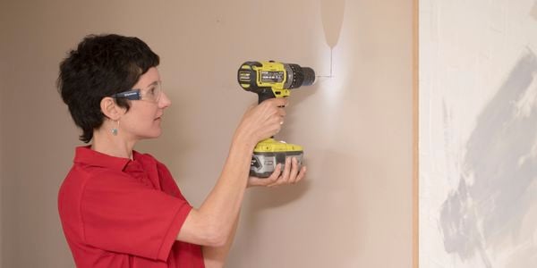 Woman using Ryobi drill with safety glasses on