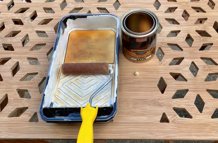Varnish is held in a paint tray with a paint brush lying on top.