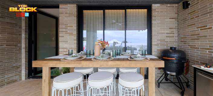 Covered outdoor entertaining area featuring a timber dining table, bar stools, brick walls and a barbecue.