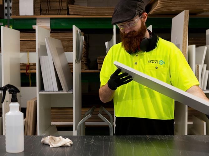 work man in green high vis top polishing island bench top