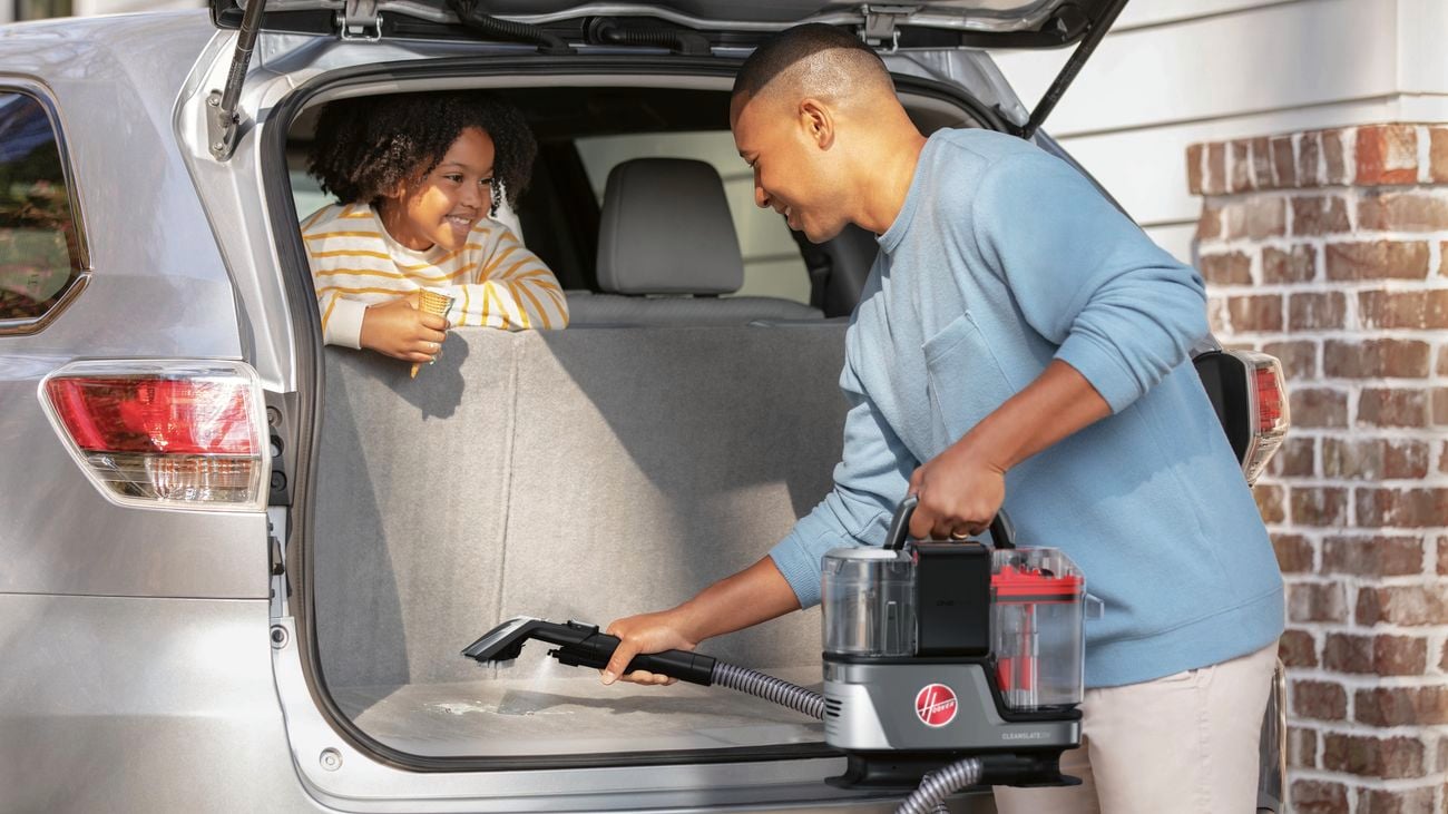 Man vacuums the boot of a car