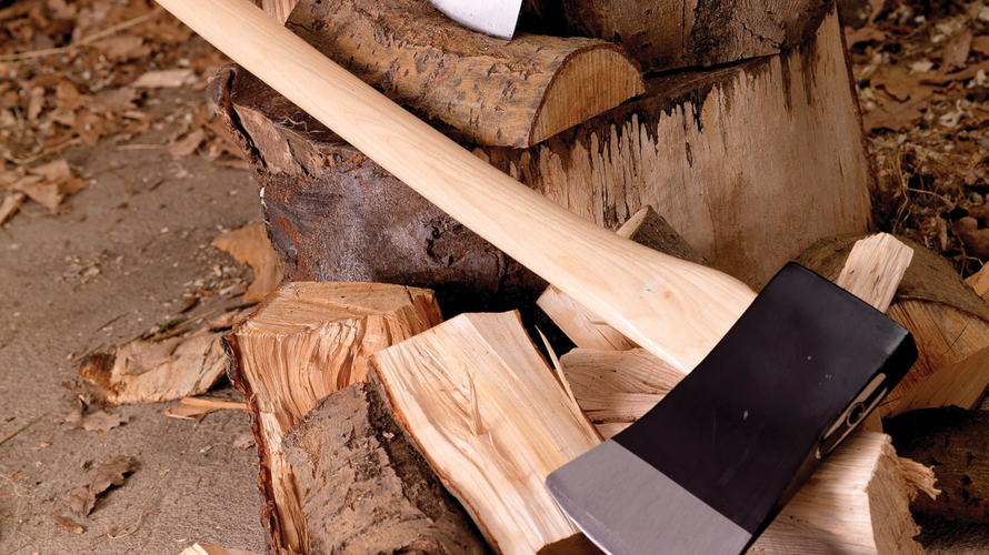 Close up of an axe lying on split logs