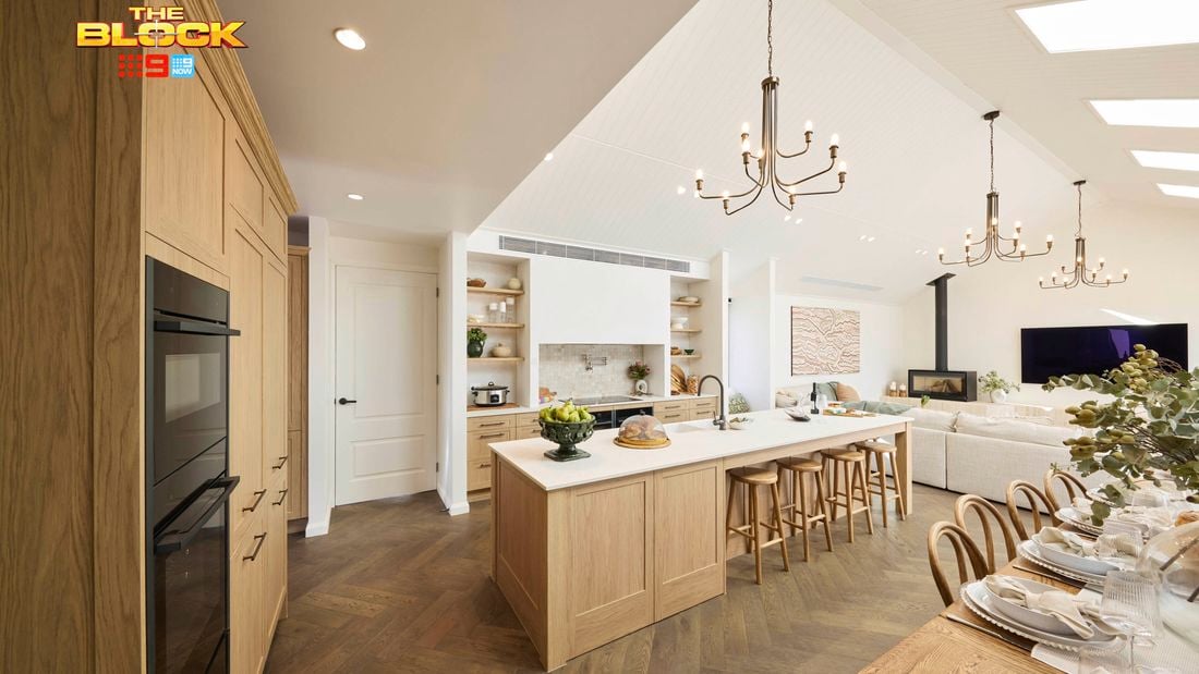 Kitchen with wooden island, open shelving, and dining table set for guests.