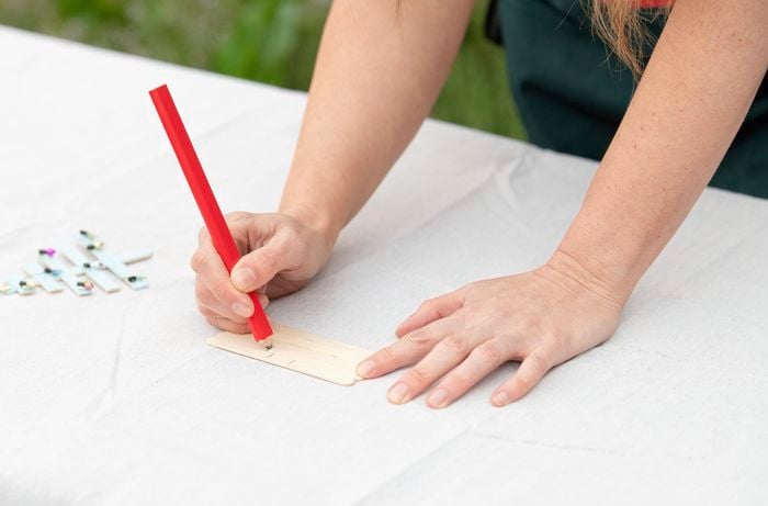 Using a pencil to make markings on a popsicle stick