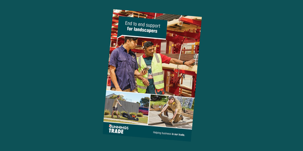 A brochure titled “End to end support for landscapers” featuring three people in a timber yard, discussing materials while standing near stacked wooden planks. Below this main image are two smaller photos: one showing landscaping equipment on a lawn, and another showing a person kneeling while working on an outdoor project. The Bunnings Trade logo and the tagline “Helping business is our trade.” appear at the bottom.