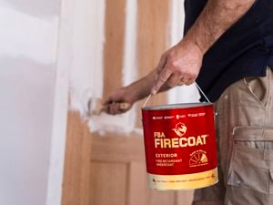 Person holding FSA FIRECOAT exterior undercoat paint, whilst painting a door.