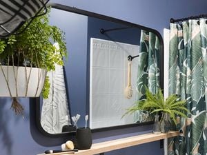 A black-framed mirror on a blue wall in a bathroom