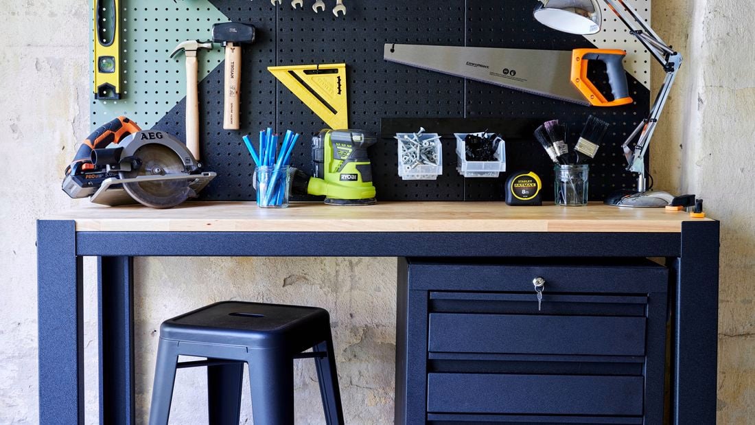 DIY Tools station with many tools attached to a wooden board and chair in front of it.