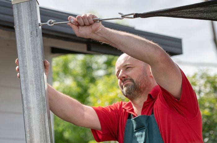 A hook and turnbuckle being added to an anchor fitting for a shade sail