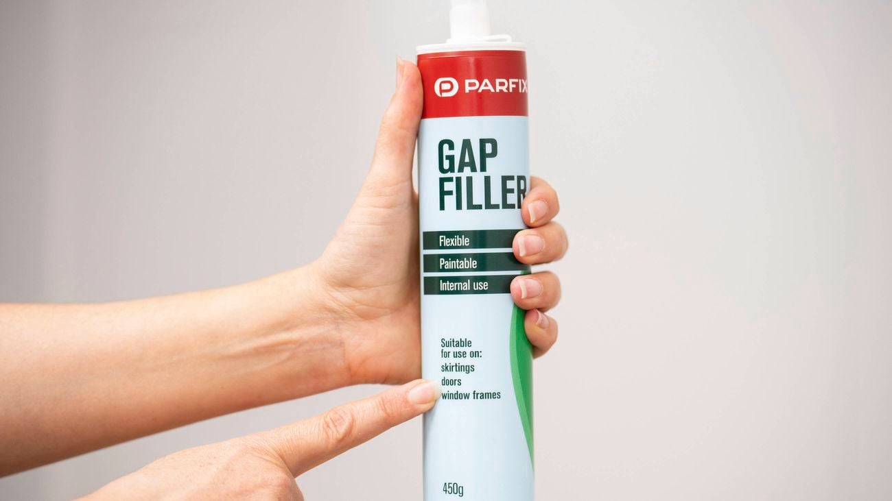 A person holding a gap filler cartridge suitable for skirting boards, doors and window frames.