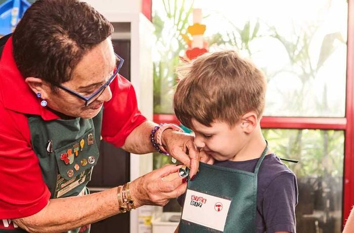 A Bunnings Team Member adding a pin to a boy with a Bunnings apron on it.
