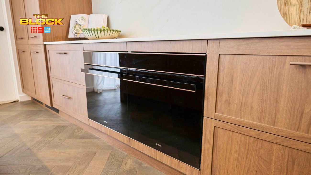 A kitchen with brown cupboards, an oven in between them and a benchtop on top of them.