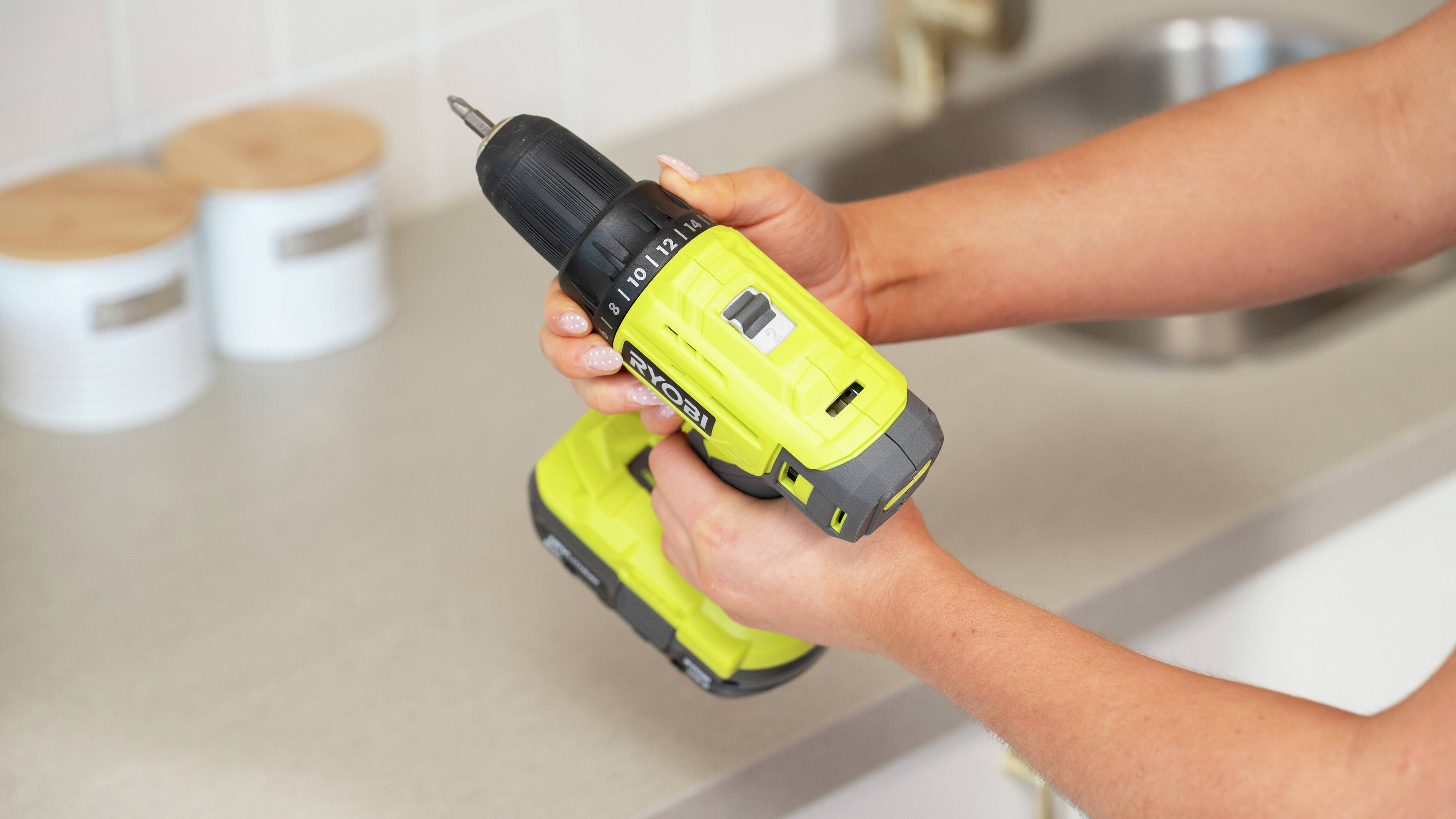 A person is using a drill driver to create a pilot hole before installing a screw during a D.I.Y. project. 