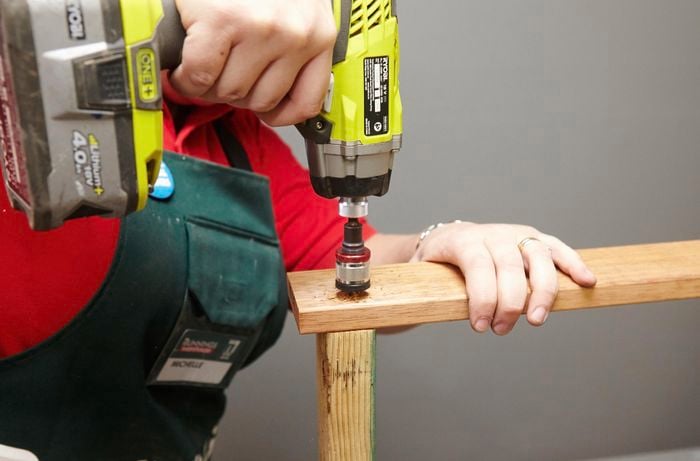 Person joining frames together with drill.
