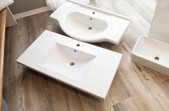 Two bathroom sinks laying side by side on hardwood floor