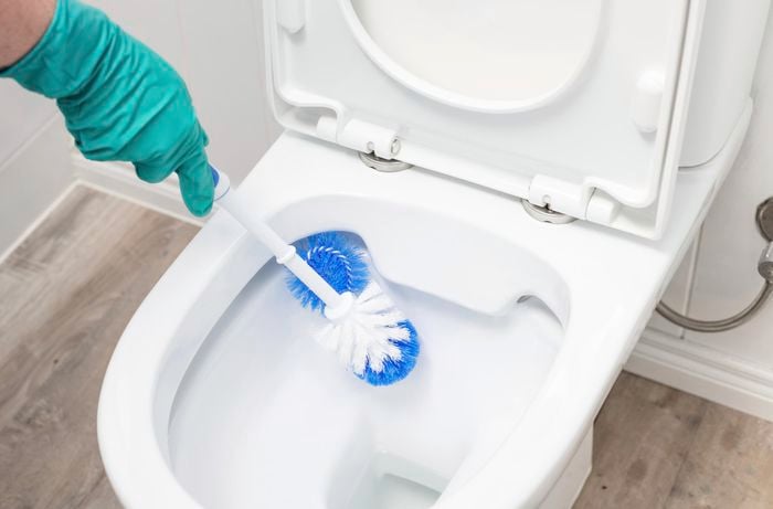 A toilet brush being used to scrub the inside of a toilet bowl