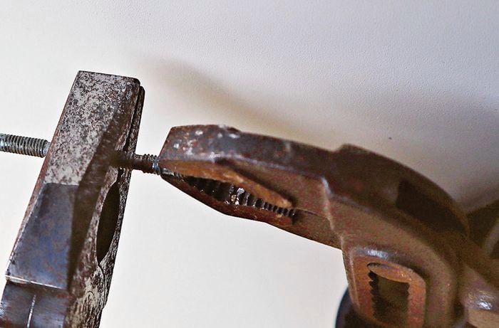 Clamp and pliers holding a screw